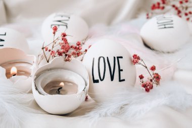 Paskalya bayramı. Kendiniz yapın. Paskalya Yumurtası Kompozisyonu. Paskalya mesajı, kalemle çizilmiş kelimeler. Masadaki kabukların yüksek açılı görüntüsü. Sevgi. Yumurta kabuğunda mum. Mum ışığı Pastel renkleri.