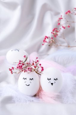 Paskalya bayramı kendin yap. Asgari paskalya konsepti. Renkli gülen yüzlü Paskalya yumurtaları ve pastel arka planda kuş tüyü. Evlenmek. Sevgililer Günü Düğün Yumurtaları. Komik yüzlü, el yapımı yumurtalı Paskalya tatili kavramı