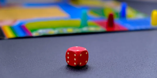 Dice for board games on black background. Board game with multi-colored cubes on table game. Monopoly. Stay home leisure activity games for kids