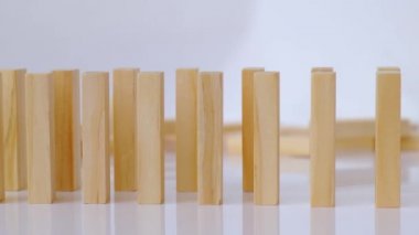 Domino etkisi, tahta domino taşlarının beyaz arka plana düşmesi. Dominolar peş peşe düşüyor, eller Domino 'yu itiyor ve zincirleme reaksiyon oyunu başlatıyor..