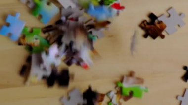 Aile eğlence zamanı. Garip şekilli iç içe geçmiş ve mozaiklenmiş yapboz parçaları. Tamamen birbirine kenetlenmiş yapboz, ahşap masaya düşüyor.