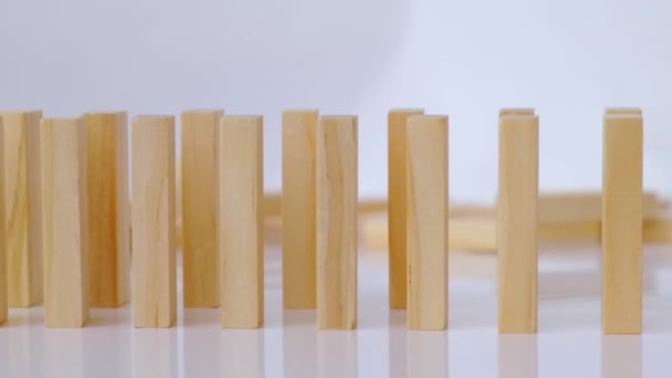 Domino αποτέλεσμα, σειρά από ξύλινο ντόμινο που πέφτει κάτω σε λευκό φόντο. Ντομίνο που πέφτουν στη σειρά, το χέρι ωθεί ένα ντόμινο και ξεκινά μια αλυσιδωτή αντίδραση Επιτραπέζιο παιχνίδι. — Αρχείο Βίντεο
