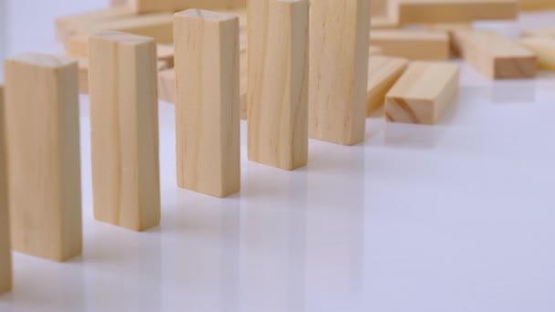 Domino hatás, egy sor fa dominó leesik fehér háttérre. Dominó esik egy sorban, kéz nyomja a Domino, és elkezd egy láncreakció Board játék. — Stock videók