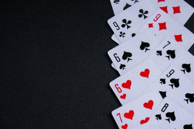 Fotokopi alanı olan siyah arkaplanda kart oynuyorum. Aileniz ve arkadaşlarınız için evde kalıp boş vakit geçirin. İskambil kağıdıyla çerçevele. Poker kartları. Poster
