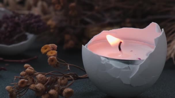 Καίγοντας κερί Μοντέρνα πασχαλινά στολίδια. Ραγισμένα βιολογικά αυγά κέλυφος με ξηρό γρασίδι και ξηρά λουλούδια κερί φως. Σκούρο φόντο. — Αρχείο Βίντεο