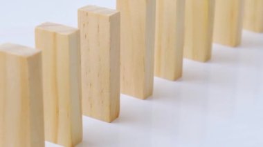 Domino etkisi, tahta domino taşlarının beyaz arka plana düşmesi. Dominolar peş peşe düşüyor, eller Domino 'yu itiyor ve zincirleme reaksiyon oyunu başlatıyor..