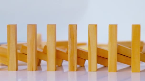 Effet domino, rangée de domino en bois tombant sur fond blanc. Dominos tomber dans une rangée, la main pousse un Domino et commence une réaction en chaîne Jeu de société. — Video