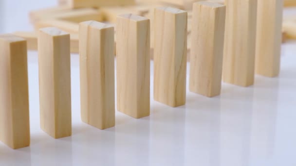 Effet domino, rangée de domino en bois tombant sur fond blanc. Dominos tomber dans une rangée, la main pousse un Domino et commence une réaction en chaîne Jeu de société. — Video