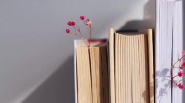 Bebek nefesli eski kitaplar yığını. Samimi bir kitap. Narin pembe çingene çiçekleri. Yavaş yaşam konsepti. Doğayla birlik. Seçici odak.