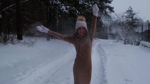 クリスマス、休日、冬の季節の概念。冬の森の自然で雪遊びをしている若い幸せな女性。スローモーション暖かい服ニット手袋と帽子. — ストック動画