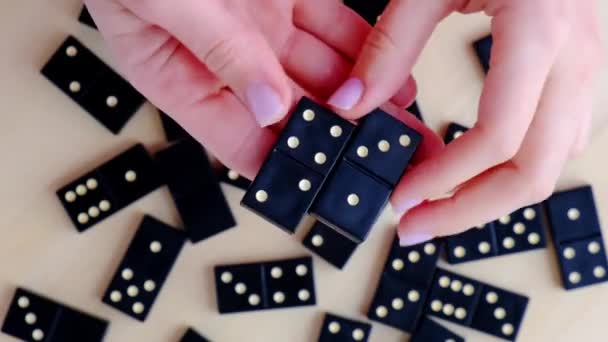 Playing dominoes on a wooden table. Womans hand with domino. Leisure games concept. Selective focus. Table game girl playing — Stock Video