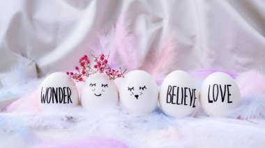 Paskalya bayramı kendin yap. Asgari paskalya konsepti. Renkli gülen yüzlü Paskalya yumurtaları ve pastel arka planda kuş tüyü. Evlenmek. Sevgililer Günü Düğün Yumurtaları. Komik yüzlü, el yapımı yumurtalı Paskalya tatili kavramı