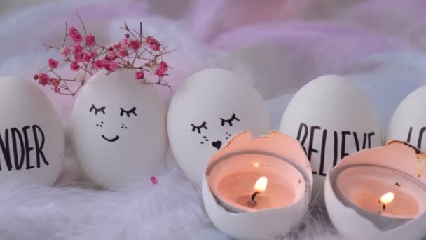 Images d'allumage d'une bougie dans des œufs de Pâques Composition. Œufs de Pâques avec des visages souriants peints. Décor intérieur confortable, bougies allumées. Des œufs de mariage. Marié. — Video