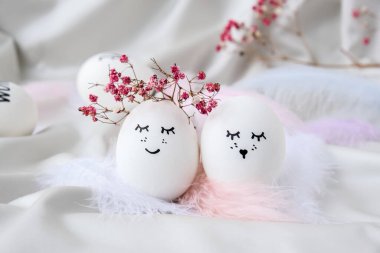 Paskalya bayramı kendin yap. Asgari paskalya konsepti. Renkli gülen yüzlü Paskalya yumurtaları ve pastel arka planda kuş tüyü. Evlenmek. Sevgililer Günü Düğün Yumurtaları. Komik yüzlü, el yapımı yumurtalı Paskalya tatili kavramı