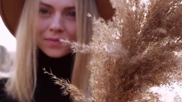 Mujer rubia europea sonriendo con sombrero beige en suéter negro en el campo. Hora dorada, casa de campo. Viajes locales. Una vida lenta. Salud mental. Hierba pampeana — Vídeos de Stock