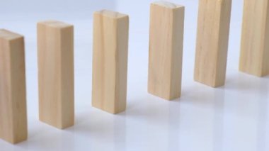 Domino etkisi, tahta domino taşlarının beyaz arka plana düşmesi. Dominolar peş peşe düşüyor, eller Domino 'yu itiyor ve zincirleme reaksiyon oyunu başlatıyor..