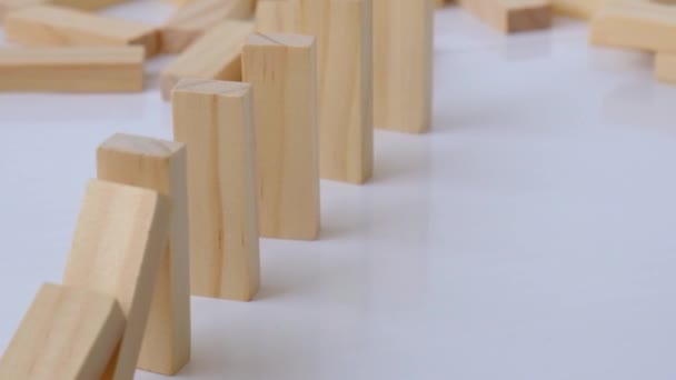 Effet domino, rangée de domino en bois tombant sur fond blanc. Dominos tomber dans une rangée, la main pousse un Domino et commence une réaction en chaîne Jeu de société. — Video