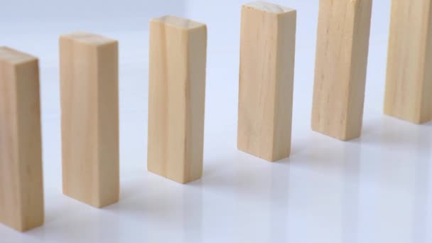 Effet domino, rangée de domino en bois tombant sur fond blanc. Dominos tomber dans une rangée, la main pousse un Domino et commence une réaction en chaîne Jeu de société. — Video