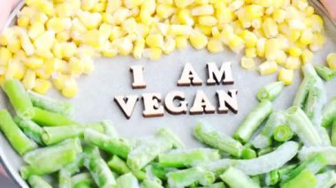 Kadın eli tut. Ben VEGAN 'ın tabağındayım. Vejetaryenlik, vejetaryen sağlıklı yaşam tarzı. Sağlıklı beslenme vegan, yeşil fasulye sarı mısır