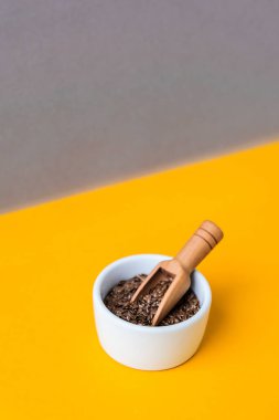 Keten tohumlu ahşap kaşık sarı zemin üzerinde beyaz bir havan topunun içinde yatıyor. Sağlıklı beslenme. Keto diyeti. Son moda vejetaryen yemekleri. Moda renklerinde izometrik tarzda minimal kavram.