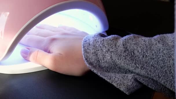 4k video ledd lampa Skönhetssalong besökare torkar bas gel på ultraviolett lampa. Nagelvård, egenvård. Gör manikyr själv medan du är hemma. Dö — Stockvideo