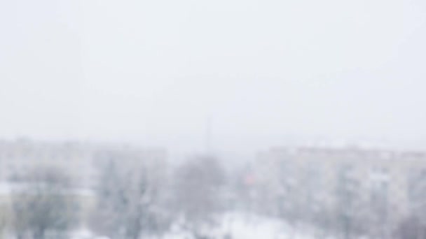 Snow falling. Snow-covered city and flying snowflakes in slow motion. Defocused. Selective focus. Blurred winter background cold weather — Stock Video