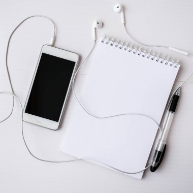 Kulaklıklı cep telefonlu boş bir defter aç. Siyah ekran ve siyah kalem. Düşman metni kopyala. Üst Manzara. Pastel renkler