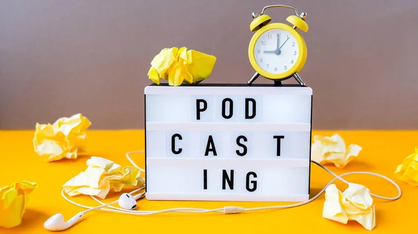 Podcasting lettering and alarm clock, headphones, crumpled yellow paper in minimalistic isometric style. Trendy colors. Grey and yellow. New technologies. Millenial. Blogger, podcaster. Audiobooks. New episode available