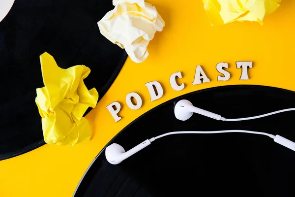 Podcast lettering and vinyl record album, headphones crumpled paper in minimalistic style on yellow background. Millenial. Blogger, podcaster. Retro style. Audiobooks. New episode available.