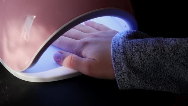 Lampada a led video 4k Il visitatore del salone di bellezza asciuga il gel di base sulla lampada ultravioletta. Cura delle unghie, cura di sé. Fai la manicure da solo mentre rimani a casa. Fai da te — Video Stock