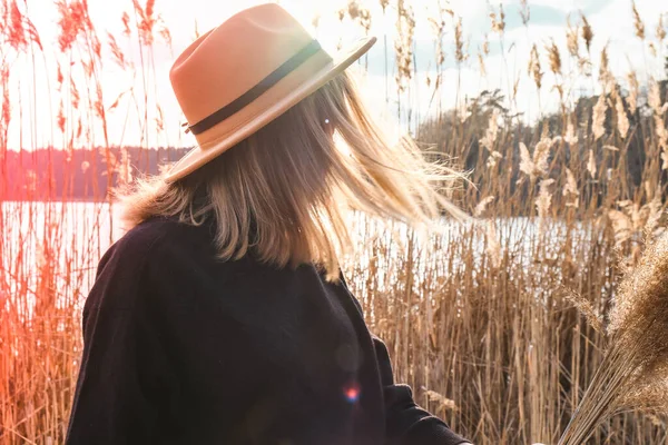 Evropská blondýnka s béžovým kloboukem v černém svetru na venkově. Zlatá hodina, Cottagecore. Místní cestování. Pomalý život. Duševní zdraví. Pampas tráva — Stock fotografie