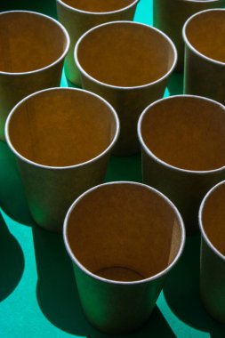 Yeşil zemin üzerinde boş geri dönüşümlü kağıt bardaklar. İçmek için bir sürü yemek fincanı. Çevre dostu. Plastiksiz sıfır konsept. Piknikler için tablo takımı