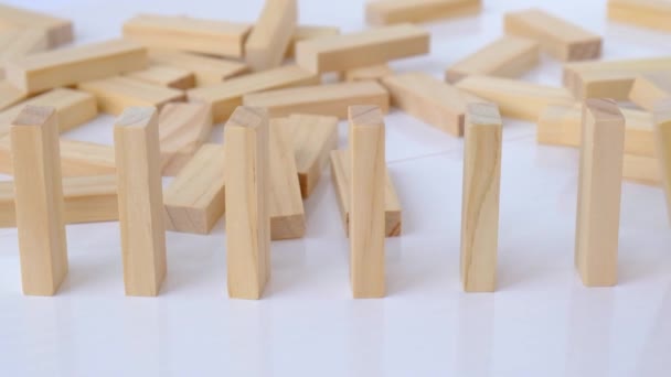 Domino-effect, rij houten domino 's op witte achtergrond. Domino 's vallen op een rij, de hand duwt een Domino en begint een kettingreactie bordspel. — Stockvideo