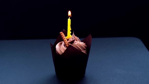 Mani femminili che fanno deliziosi cupcake al cioccolato con crema su sfondo scuro. Muffin al cioccolato fatto in casa. Torta di compleanno con candela accesa. Fiamma. Soffiando. — Video Stock