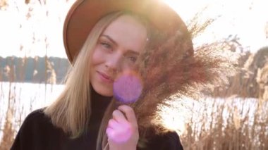 4k Kafkasyalı sarışın kadın kırsalda bej şapkalı, siyah kazaklı otlar sallıyor. Altın saat, Cottagecore. Yerel seyahat. Yavaş yaşam. Ruh Sağlığı