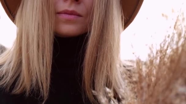 Donna bionda europea sorridente con cappello beige in maglione nero in campagna. Ora d'oro, Cotttagecore. Viaggi locali. Una vita lenta. Salute mentale. Erba di pampas — Video Stock