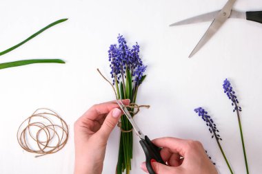 Dişi eller hediye olarak bir buket mavi muscari toplar. Çiçek buduyorum. Çiçekçide çiçekçi. Eko-tarz. İş yerindeki çiçekçi. Buket yapan kadın