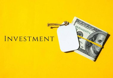 Lastik banttaki dolar parası, INVESTMENT yazılı not, servet kurucu zihniyeti, kendine yatırım yapmak ve büyümek için küçük miktarda para ayarlamayı hatırlat