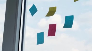 4K kadın proje yöneticisi renkli çıkartmalar değiştiriyor, cam duvarda çalışma süreci planlıyor. İş akışını yöneten motive iş kadını