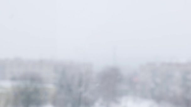 Nieve cayendo. Ciudad cubierta de nieve y copos de nieve voladores en cámara lenta. Desenfocado. Enfoque selectivo. Fondo de invierno borroso clima frío — Vídeos de Stock