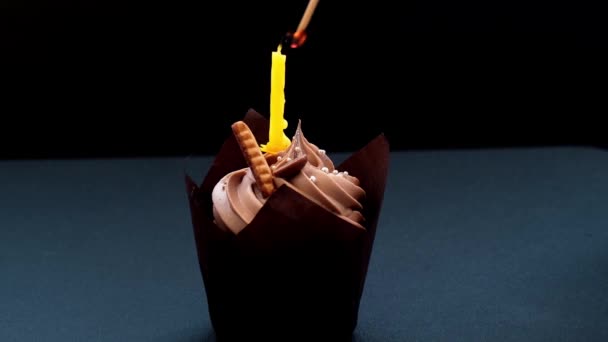 Weibliche Hände machen köstliche Schokoladen-Cupcakes mit Sahne auf dunklem Hintergrund. Hausgemachter Schokoladenmuffin. Geburtstagstorte mit brennender Kerze. Flamme. Ausgeblasen. — Stockvideo