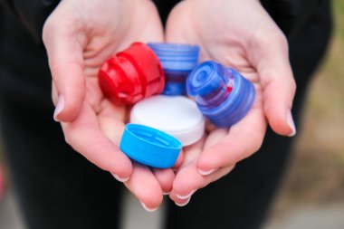Kafkas kadınlarının elleri renkli plastik bardaklarla dolu, bir avuç dolusu plastik kapak israfı. Geri dönüşüm. Şişe kapakları topluyorum. Çevre kavramı