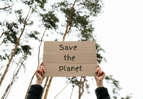女性手拿着印有文字的硬纸板在户外拯救星球 自然背景 抗议者积极分子 社会行动主义 — 图库照片