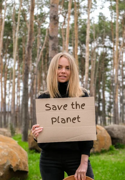 Portret van een blanke jongedame met een kartonnen hoed met tekst SAVE THE PLANET outdoor. Natuur achtergrond. Demonstrant activist — Stockfoto