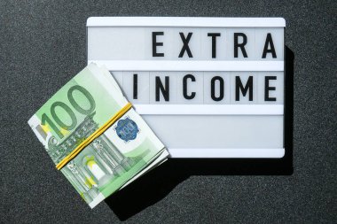 İçinde Avro banknotları etrafında siyah harflerle ExTRA gelir yazan ışık panosu. Para, iş, finans, yatırım, tasarruf. Nakit para. Zenginlik ve refah finansmanı iş bütçesi. Pasif gelir