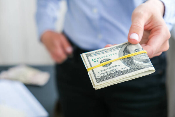 Деловая женщина, кладущая пачку наличных долларов США. Крупный план. Концепция доходов и бизнеса. Венальность, взятка, коррупция. Рука дает деньги. Тысячелетние откровенные подлинные женские руки, считая деньги USD. Бизнес-бюджет благосостояния и процветания