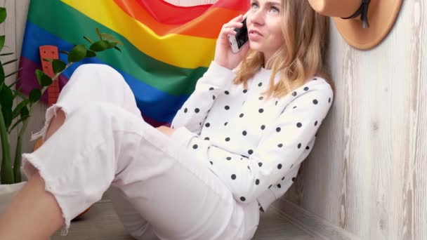 4k Młoda hipisowska hipiska siedząca na balkonie za pomocą telefonu komórkowego. Tęczowa flaga LGBTQ na tle. SMS-y, rozmowy wideo, robienie selfie. Blogerka. Randki online. Praca w domu. — Wideo stockowe