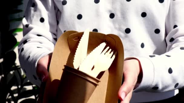 Movimento lento Mãos femininas segurando garfos de madeira e copos de papel com placas. Eco amigável utensílios de mesa descartáveis. Usado em fast food, restaurantes, takeaways, piqueniques. Sem plástico — Vídeo de Stock