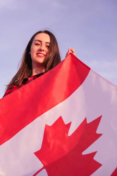 年轻的千年黑发女子举着加拿大国旗。加拿大国旗或枫叶。游客或爱国心。移民到一个自由的国家。独立日7月1日 — 图库照片