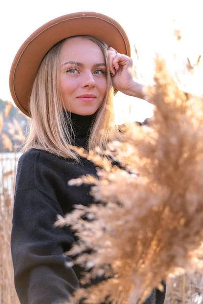 Mujer rubia europea con sombrero beige en suéter negro en el campo. Hora dorada, casa de campo. Viajes locales. Una vida lenta. Salud mental. Hierba pampeana —  Fotos de Stock